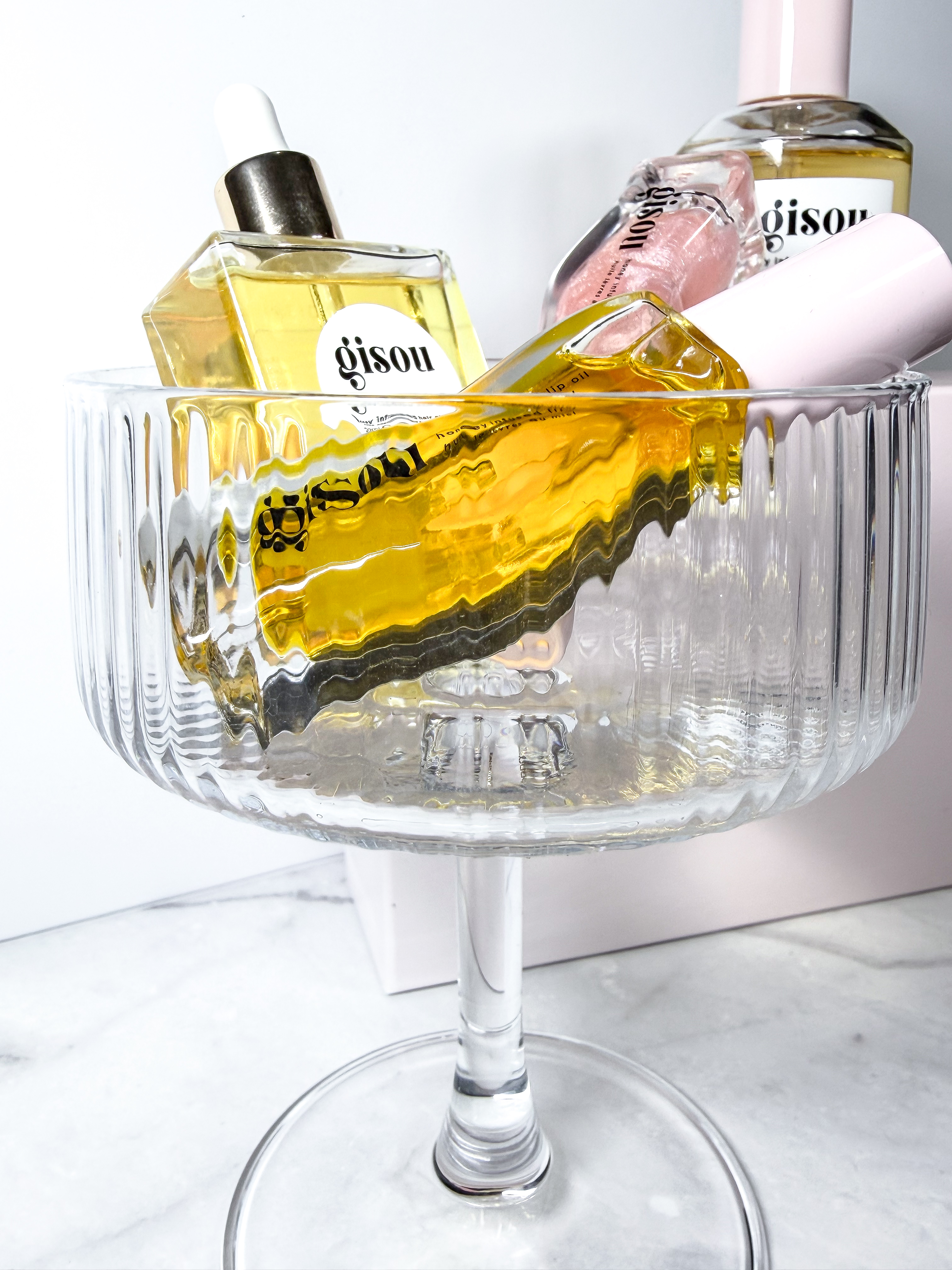 Gisou honey-infused range styled in a fluted glass coupe for an editorial brand feature by Beauty With Ju