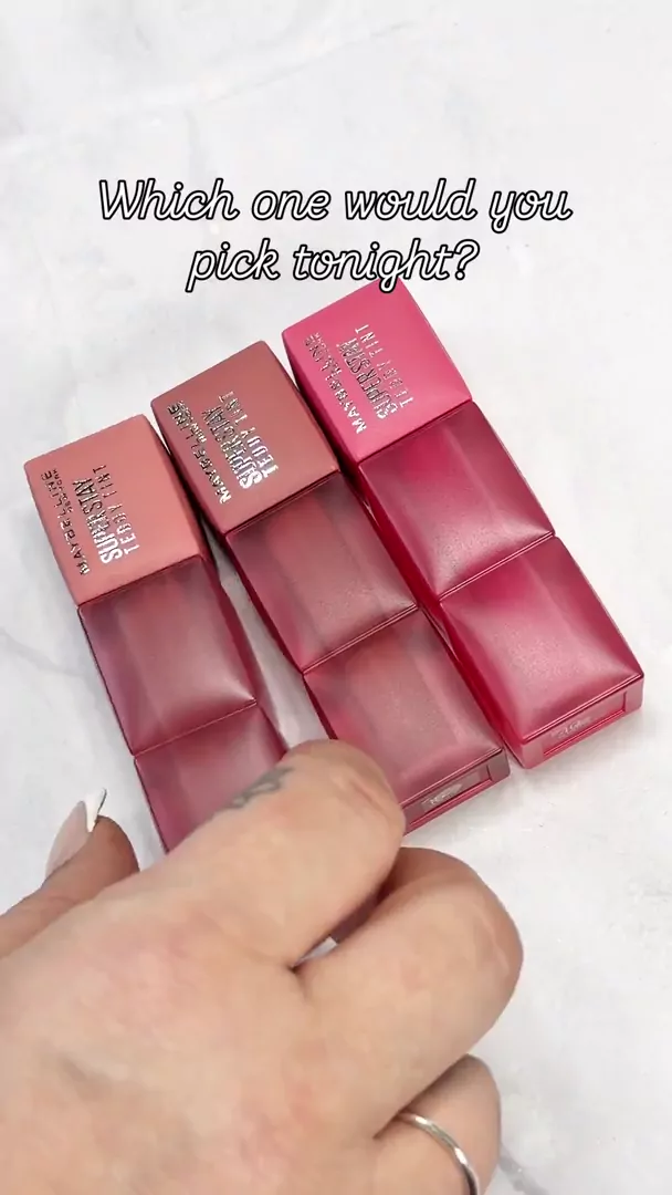Three pink and berry lip tint tubes arranged on a white marble surface with bright, natural lighting