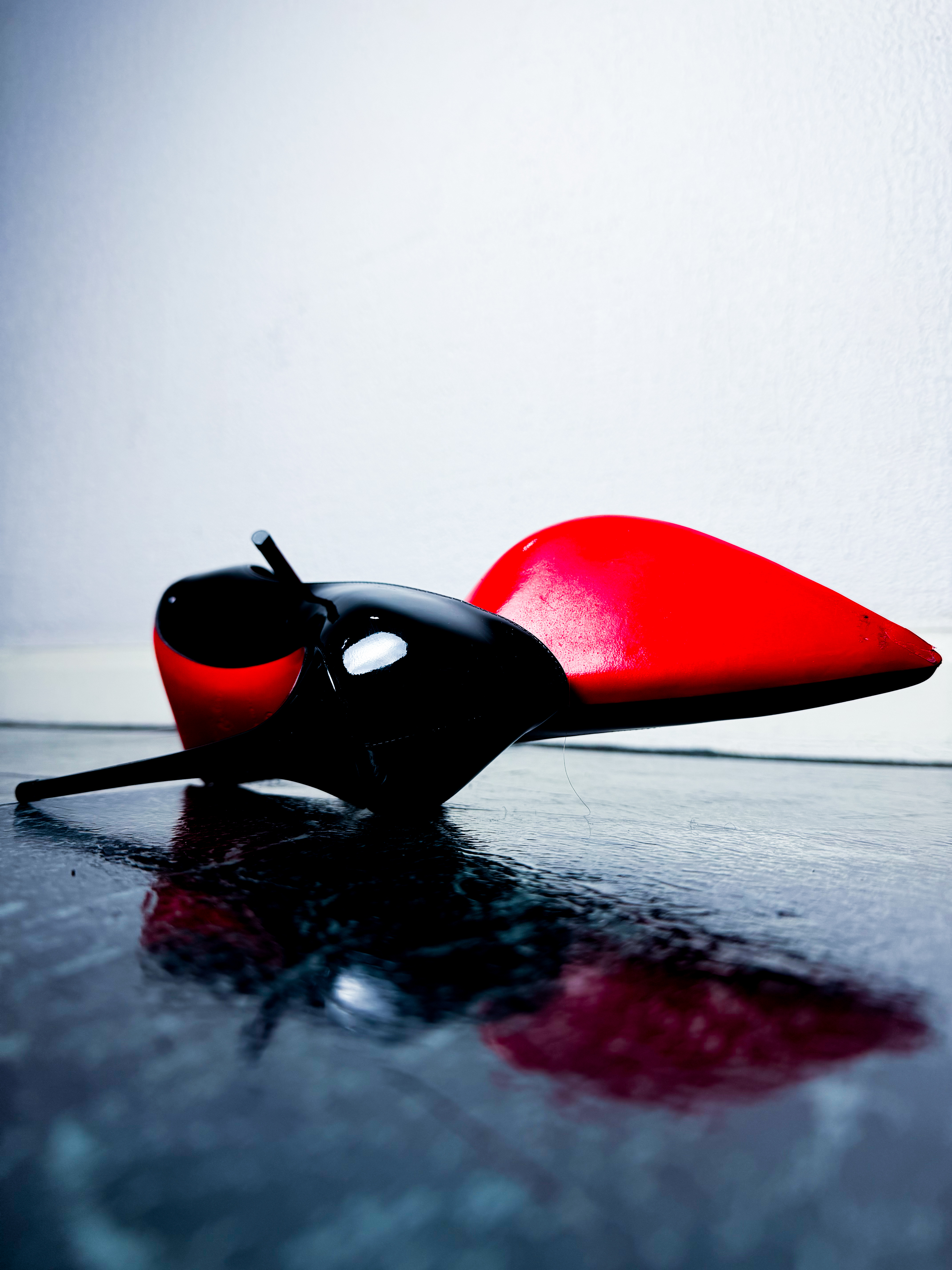 Christian Louboutin Kate 100 red heel editorial product shot on wet surface, luxury fashion UGC content UK
