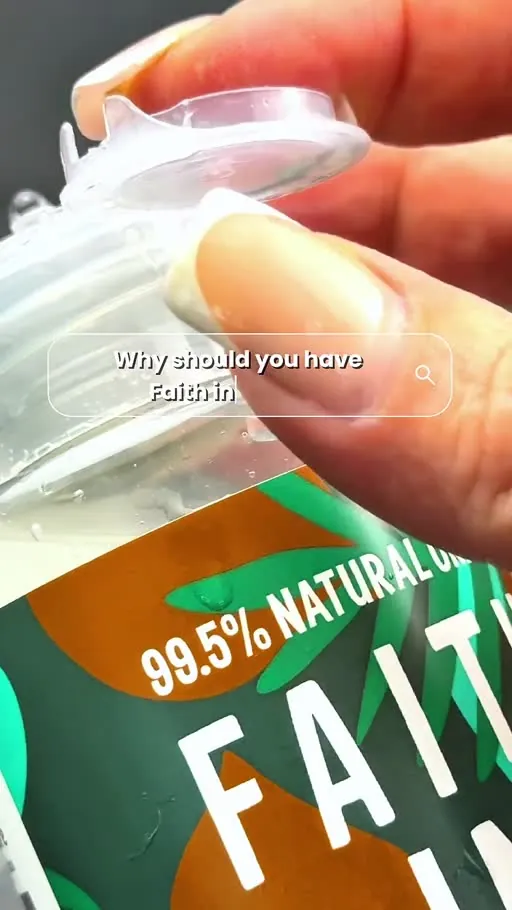 Close up of fingers opening a clear flip-top bottle cap with bright light reflecting off the surface and green label.